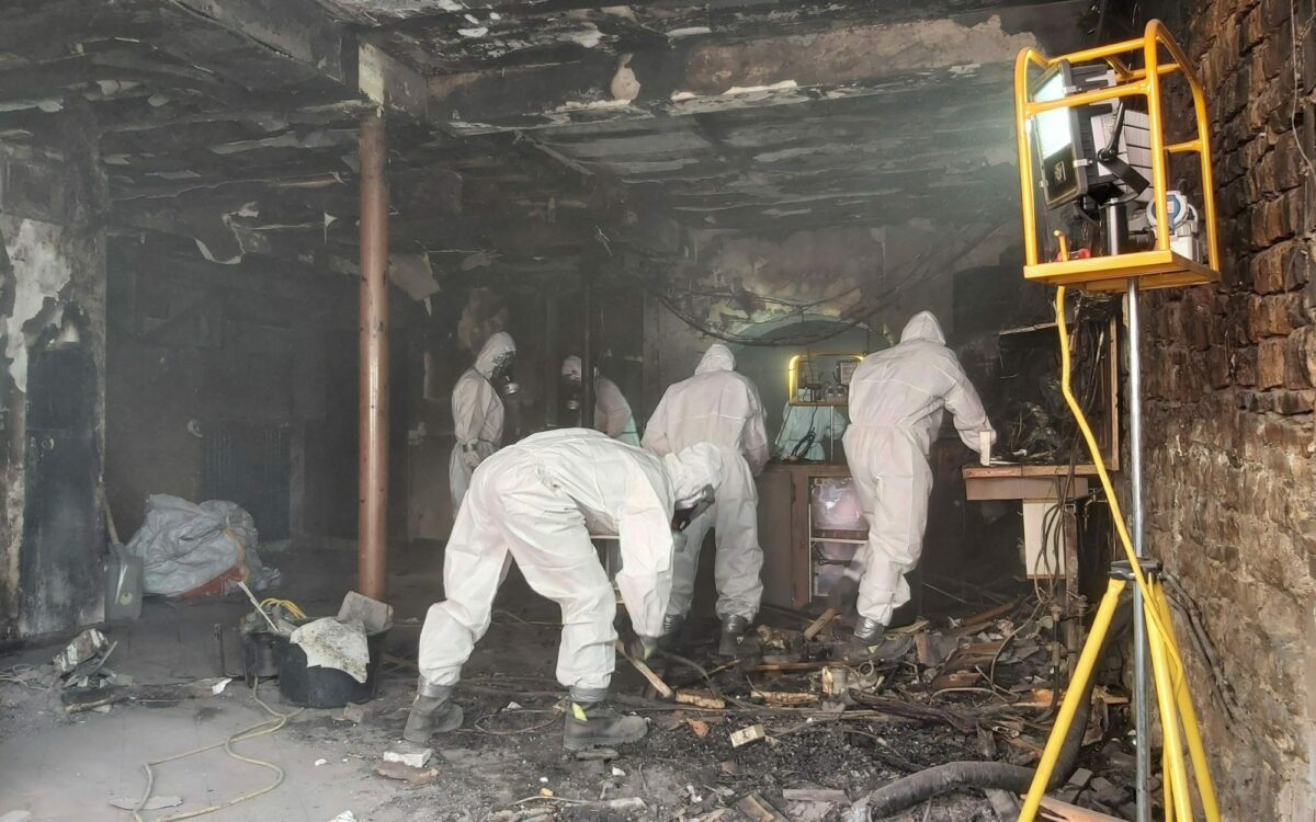 Feuerwehrleute mit schutzanzuegen am ausraeumen Feuerwehrleute mit schutzanzuegen am ausraeumen